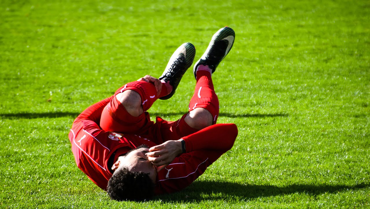 Soccer playing laying on field with a calf cramp