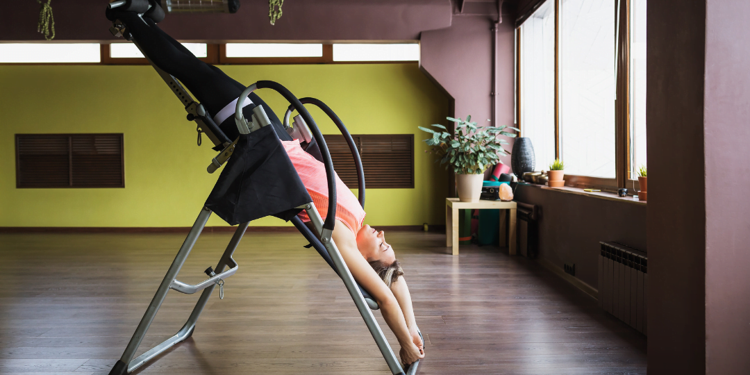 Woman hanging from inversion table in a gym